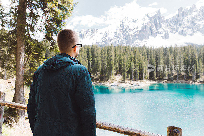 在Dolomites阿尔卑斯山，一名戴眼镜的男子正在欣赏阳光明媚的Lago Di Carezza湖